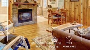 Mamaw's Cabin with a stone fireplace, wooden walls, a dining area, and a ceiling fan.
