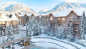 A resort with a pool area, snow-covered trees, and mountain views. - Peaceful Penthouse – Sunrise Views & Resort Amenities! (Canmore)