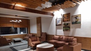 A modern lounge area with a sectional sofa, armchairs, a coffee table, and artwork on the walls. - Jay Clarks Exotica (Nahan)