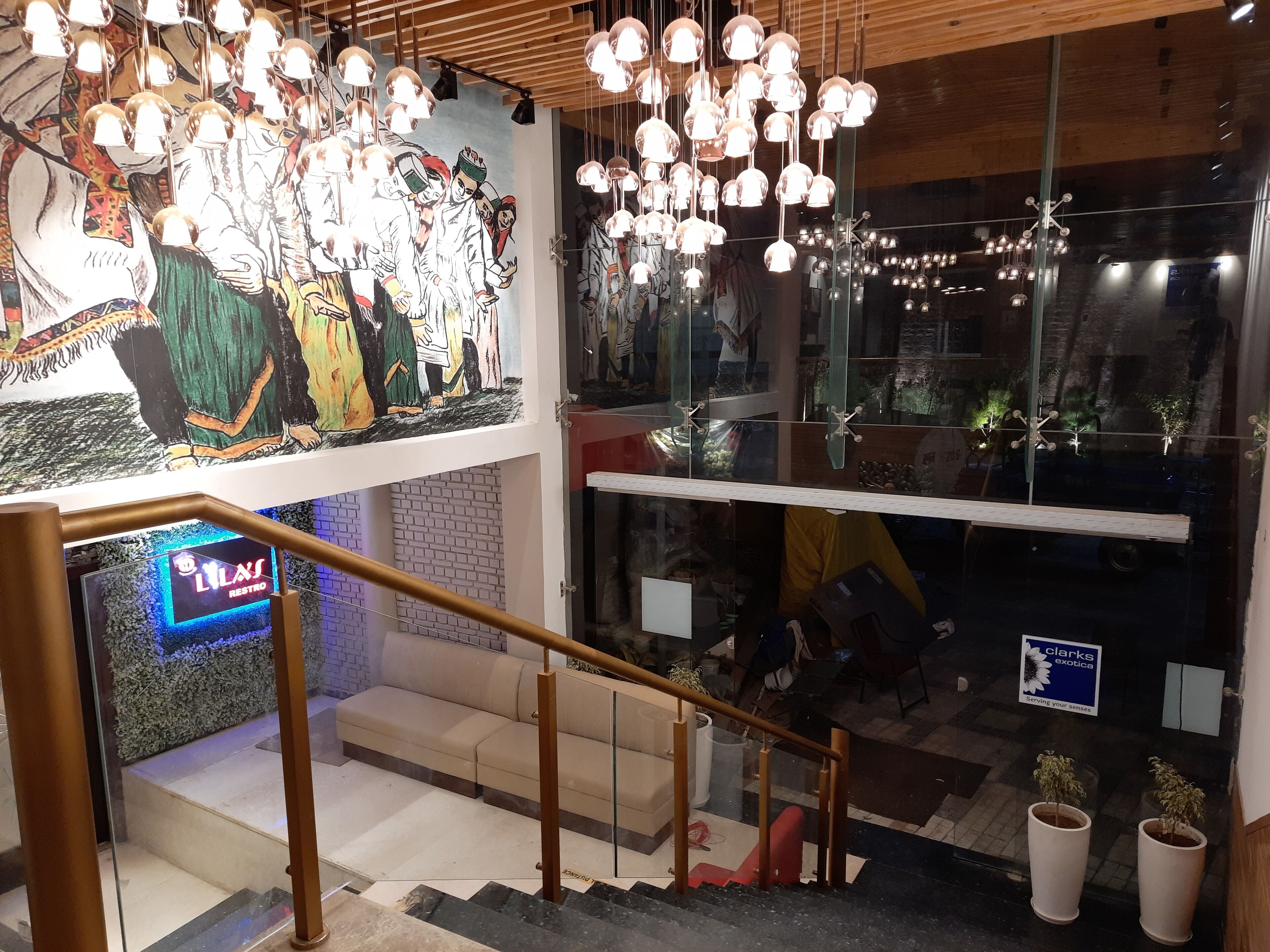 A modern interior with a staircase, a mural, and hanging lights.