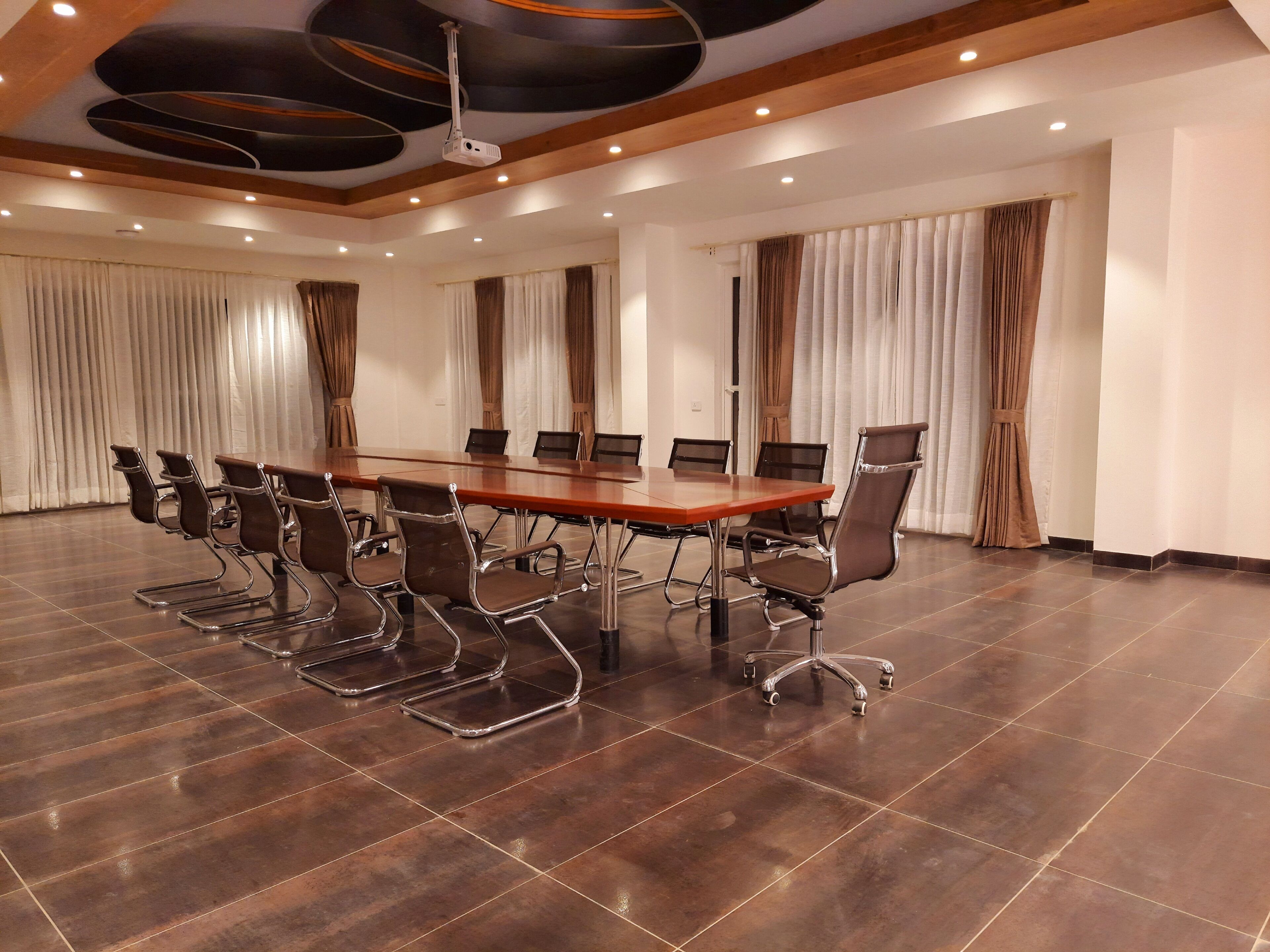 A conference room with a long table, multiple chairs, and a ceiling projector.