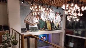 A staircase with a handrail, a mural of people in traditional attire, and a neon sign for 'TLA'S'. - Jay Clarks Exotica (Nahan)