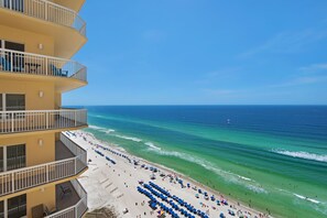 Ein Strandhotel mit mehreren Balkonen, einem Sandstrand und Blick auf den Ozean.