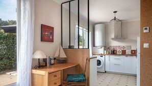 A compact kitchen with a washing machine, a wooden desk with a chair, and a large mirror. - House avec jardin à 140m de la Plage (Saint-Michel-Chef-Chef)