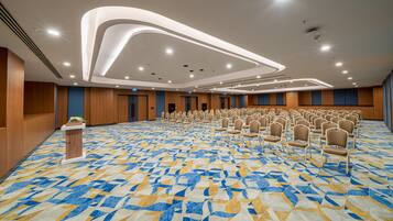 A conference room with rows of chairs, a podium, and a patterned carpet.