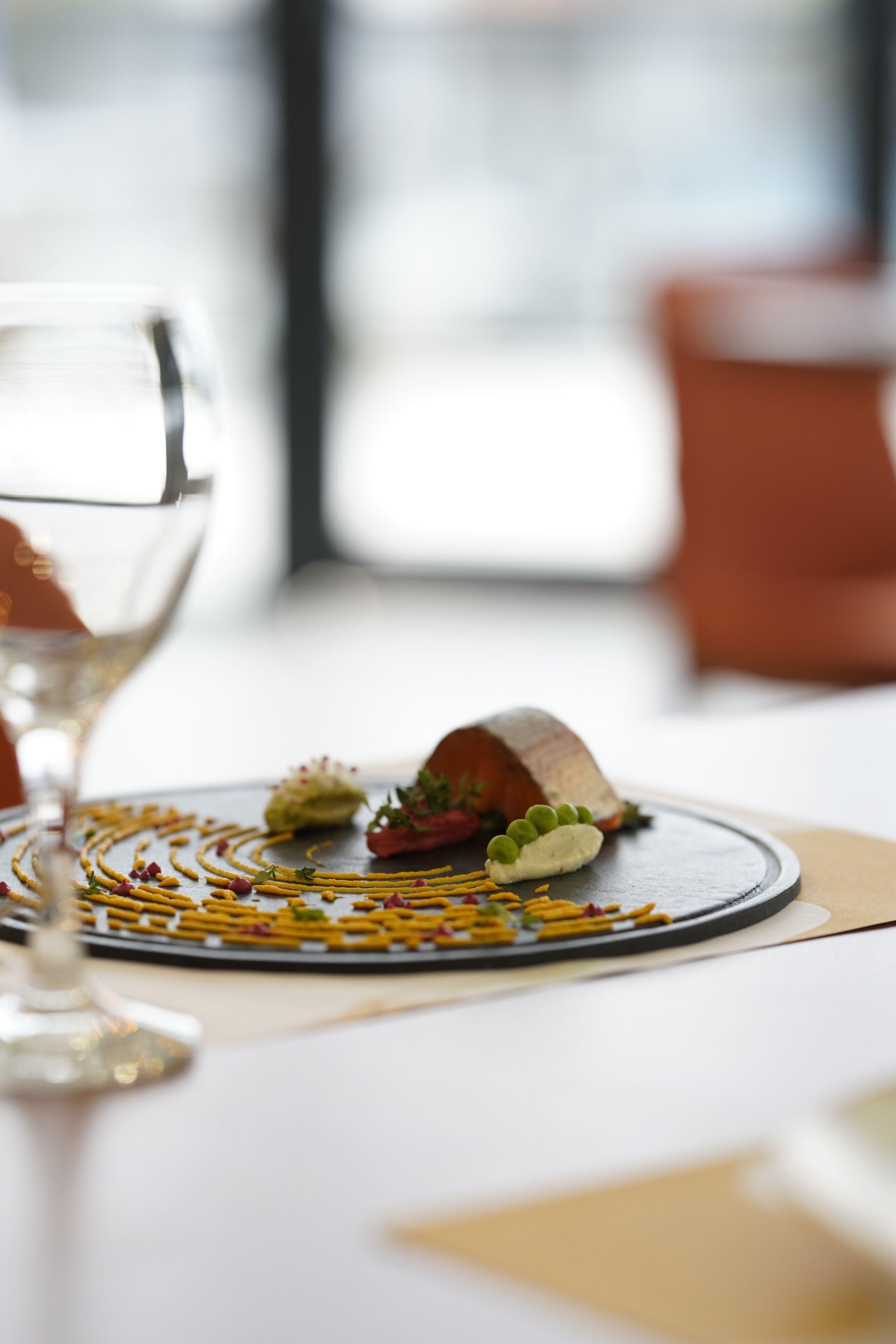 A dining table with a plate of food and a glass of wine.