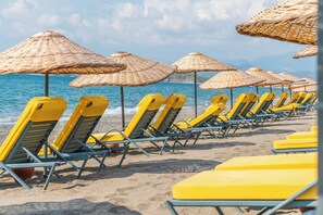 En la playa, sillas reclinables de playa, sombrillas, toallas de playa