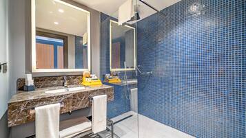 A bathroom with a marble sink, a large mirror, and blue mosaic tiles.