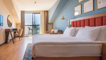 Ein Hotelzimmer mit einem großen Bett, einem Schreibtisch und einem Stuhl. Es gibt einen Balkon mit Blick.