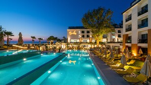 Un hôtel doté d’une piscine, de chaises longues et offrant une vue sur la mer.