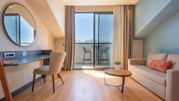 Una sala moderna con un sofá, una mesa de comedor y sillas. Hay un balcón con vista a la ciudad.