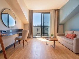 A modern living room with a sofa, a dining table, and chairs. There is a balcony with a view of the city.