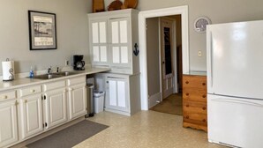 A kitchen with white cabinets, a sink, a coffee maker, and a refrigerator. - Charming 3rd Floor Walk-up River View (Clayton)
