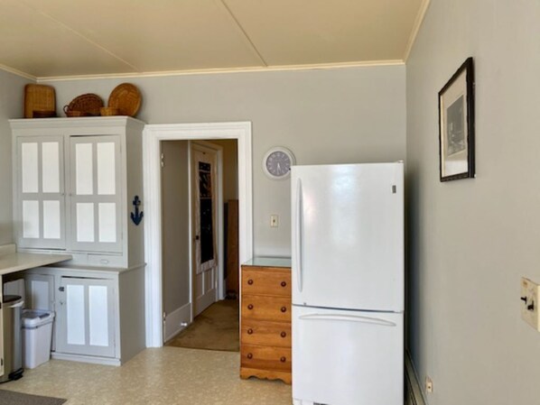 A compact kitchen with white cabinetry, a white refrigerator, and a wooden dresser. - Charming 3rd Floor Walk-up River View (Clayton)