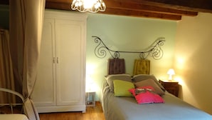 A bedroom with a bed, bedside lamps, a wardrobe, and a chandelier.