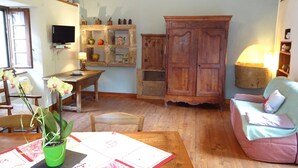 A cozy living room with a wooden table, a green potted plant, a wooden cabinet, and a pink sofa.