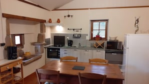 A kitchen with a wooden table and chairs, a stove, oven, microwave, and a refrigerator.