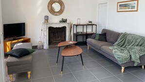 Un salon avec une cheminée, un téléviseur, un canapé et une table basse.
