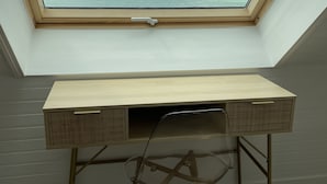 Une lucarne donnant sur la mer, un bureau en bois et une chaise dans une pièce.
