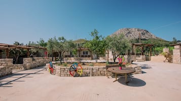 A courtyard with stone walls, a wooden pergola, and a table with chairs.