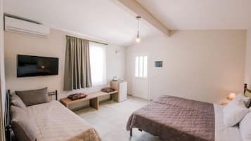 A bedroom with two beds, a TV, a desk, a window with curtains, and a door.