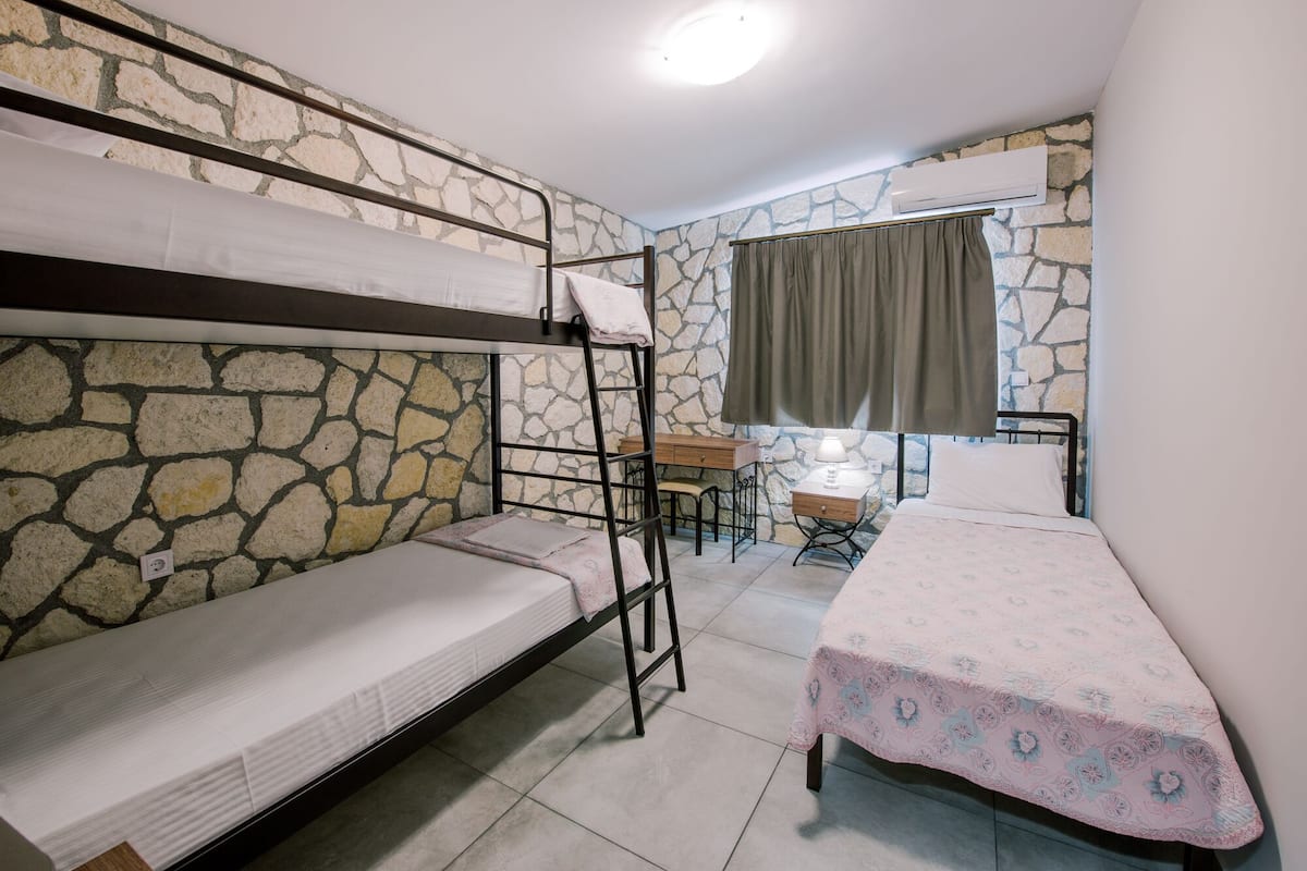 A dormitory room with bunk beds, a desk, and a single bed.