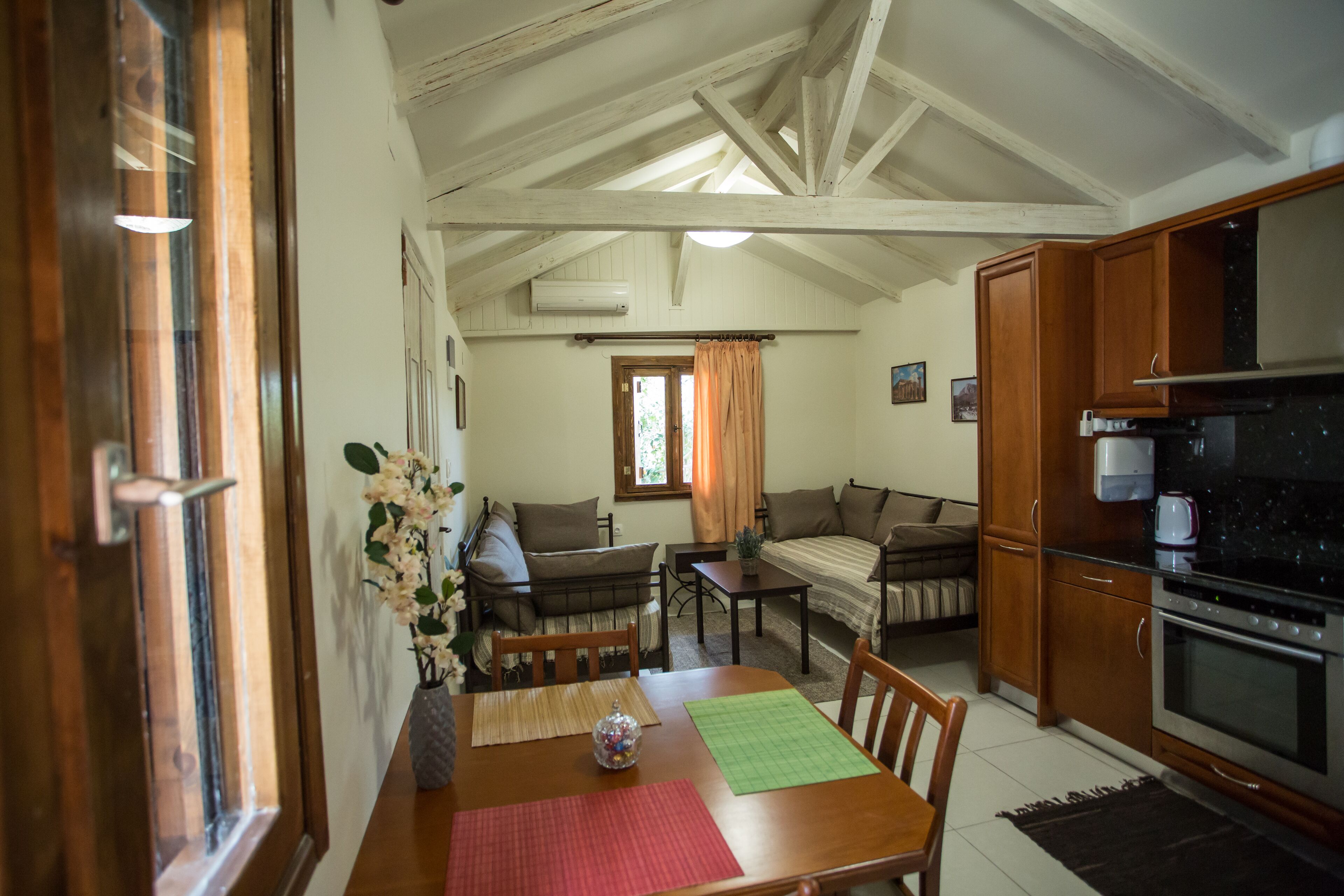Uma área de estar acolhedora com uma mesa de jantar de madeira, um sofá e uma cozinha com fogão.