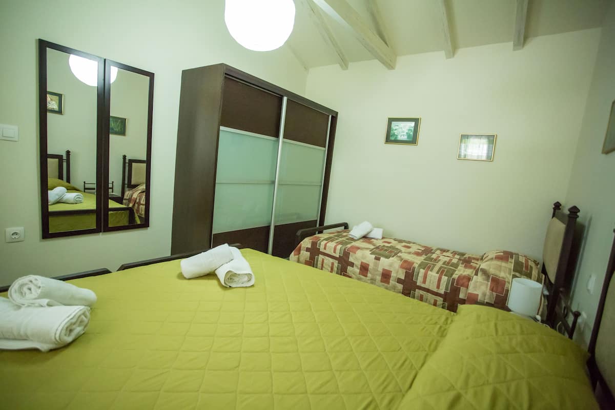 A hotel room with a large bed, a wardrobe, a mirror, and two framed pictures on the wall.