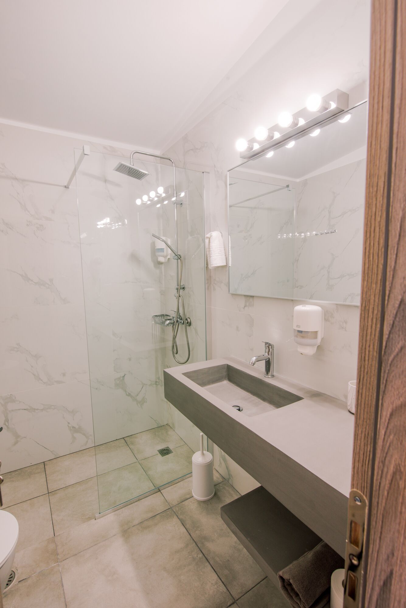 Une salle de bain moderne dotée d’une douche à parois de verre, d’un grand miroir et d’un meuble-lavabo à deux vasques.