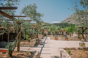 A rustic outdoor area with stone walls, wooden pergolas, and olive trees. - Acrocorinth Apartments (Corinth)