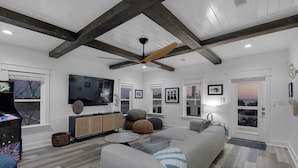 A modern living room with a grey sofa, a flat-screen TV, and a ceiling fan. - PRIVATE  POOL! 6 SEAT GOLF CART!  VOLLEYBALL COURT! 2 MIN. WALK TO BEACH! (Santa Rosa Beach)