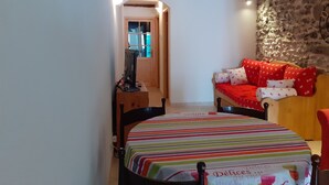 A cozy room with a bed, a wooden desk, and a stone wall. - Charmant Appartement de Village (La Brigue)
