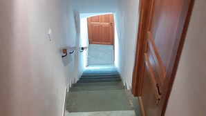 A narrow stairway leading to a room with a wooden door and a small window. - Charmant Appartement de Village (La Brigue)