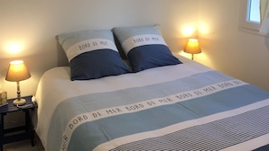 Une chambre à coucher avec un lit, deux lampes de chevet et trois tableaux encadrés accrochés au mur.