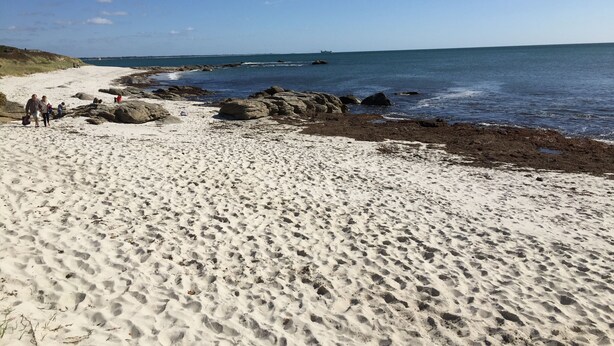Une plage de sable avec des rochers et un ciel bleu clair.