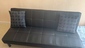 Un sofá de cuero negro con un diseño de cuadrícula y dos almohadones estampados.