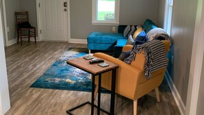 Una sala de estar con un sofá azul, una mesa de centro de madera y un ventilador de techo.
