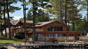 A lodge with a dock, wooden exterior, and a 'NOW OPEN' sign.