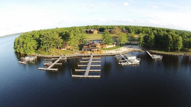 A lakeside property with a dock, boats, and a lodge surrounded by trees.