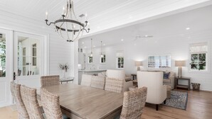 A spacious dining area with a wooden table and wicker chairs, a chandelier, and a ceiling fan. - Access to Fitness Center and 4 Pools (Inlet Beach)