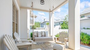 A covered patio with white Adirondack chairs, a sofa, and a swing. - Access to Fitness Center and 4 Pools (Inlet Beach)