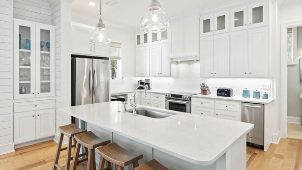 A modern kitchen with white cabinetry, stainless steel appliances, and a large island with bar stools. - Access to Fitness Center and 4 Pools (Inlet Beach)