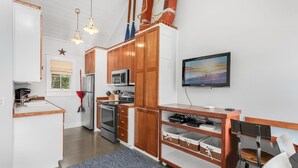 Eine moderne Küche mit Holzschränken, Edelstahlgeräten und einem Flachbildfernseher an der Wand.