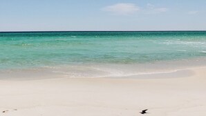Ein Strand mit klarem türkisblauem Wasser und einem weißen, sandigen Ufer.