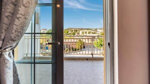 Ein Balkon mit freiem Blick auf Gebäude und Grün im Hintergrund.