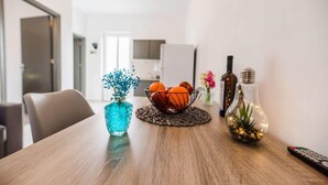 Une table à manger ornée d’un vase bleu, d’un panier de fruits et d’un vase décoratif contenant des plantes.