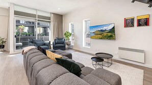 Una sala de estar moderna con un sofá seccional gris, una mesita redonda y un ventanal que ofrece vistas al exterior.
