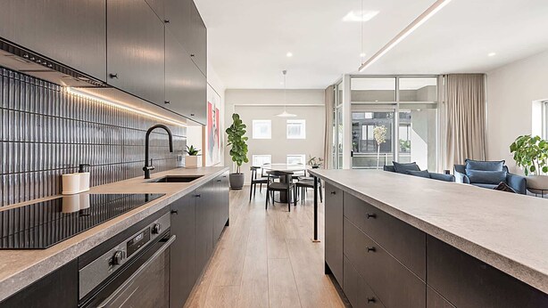 Una cocina moderna con una isla central, electrodomésticos integrados y una zona de comedor con vistas.