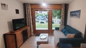 Un salon avec un téléviseur, un meuble en bois, un canapé et une table sur laquelle se trouve un plateau.