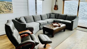 Un salon moderne avec un canapé d’angle, un fauteuil en cuir et une table basse.